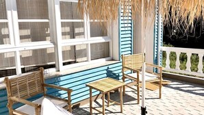 Ett område vid poolen med en blå pool, trämöbler och ett parasoll med tak av halm.