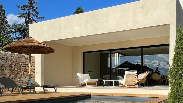 A modern outdoor pool area with lounge chairs and a dining table.