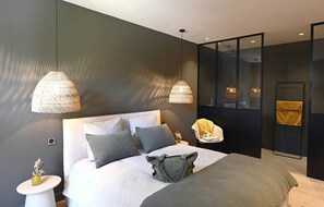 Un dormitorio moderno con una cama grande, dos lámparas colgantes, una mesita de noche y una silla.
