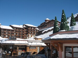 Ein schneebedecktes Resort mit mehrstöckigen Gebäuden, Außenbereichen zum Sitzen und schneebedeckten Bäumen.