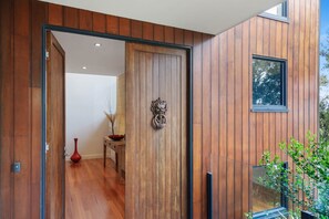 A wooden interior with a sliding door, a vase, and a window. - St Johns Wood Treehouse (Blairgowrie)