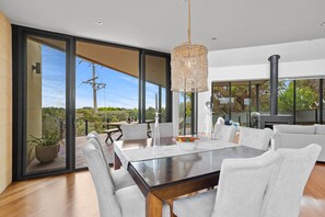 A modern dining area with a large table, chairs, and a hanging light fixture. - St Johns Wood Treehouse (Blairgowrie)