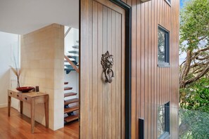Ein modernes Interieur mit einer Holztür, einer Treppe und einem Essbereich mit Tisch und Stühlen.