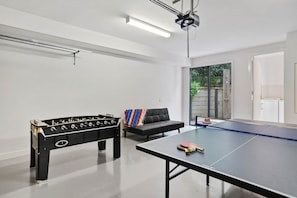 A room with a foosball table, a ping pong table, and a sofa. - St Johns Wood Treehouse (Blairgowrie)