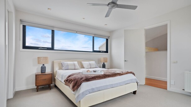 Ein Schlafzimmer mit Bett, Nachttischen, einem Deckenventilator und einem Fenster mit Blick.
