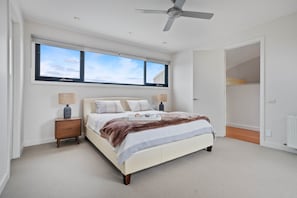 A bedroom with a bed, nightstands, a ceiling fan, and a window with a view. - St Johns Wood Treehouse (Blairgowrie)