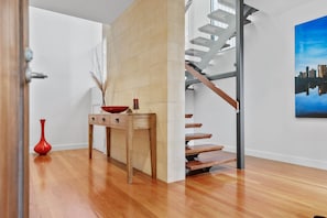 A modern interior with a wooden floor, a staircase with a metal railing, and a painting on the wall. - St Johns Wood Treehouse (Blairgowrie)