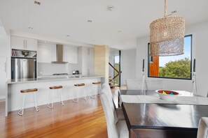 A modern kitchen with a central island, bar stools, and a hanging light fixture. - St Johns Wood Treehouse (Blairgowrie)