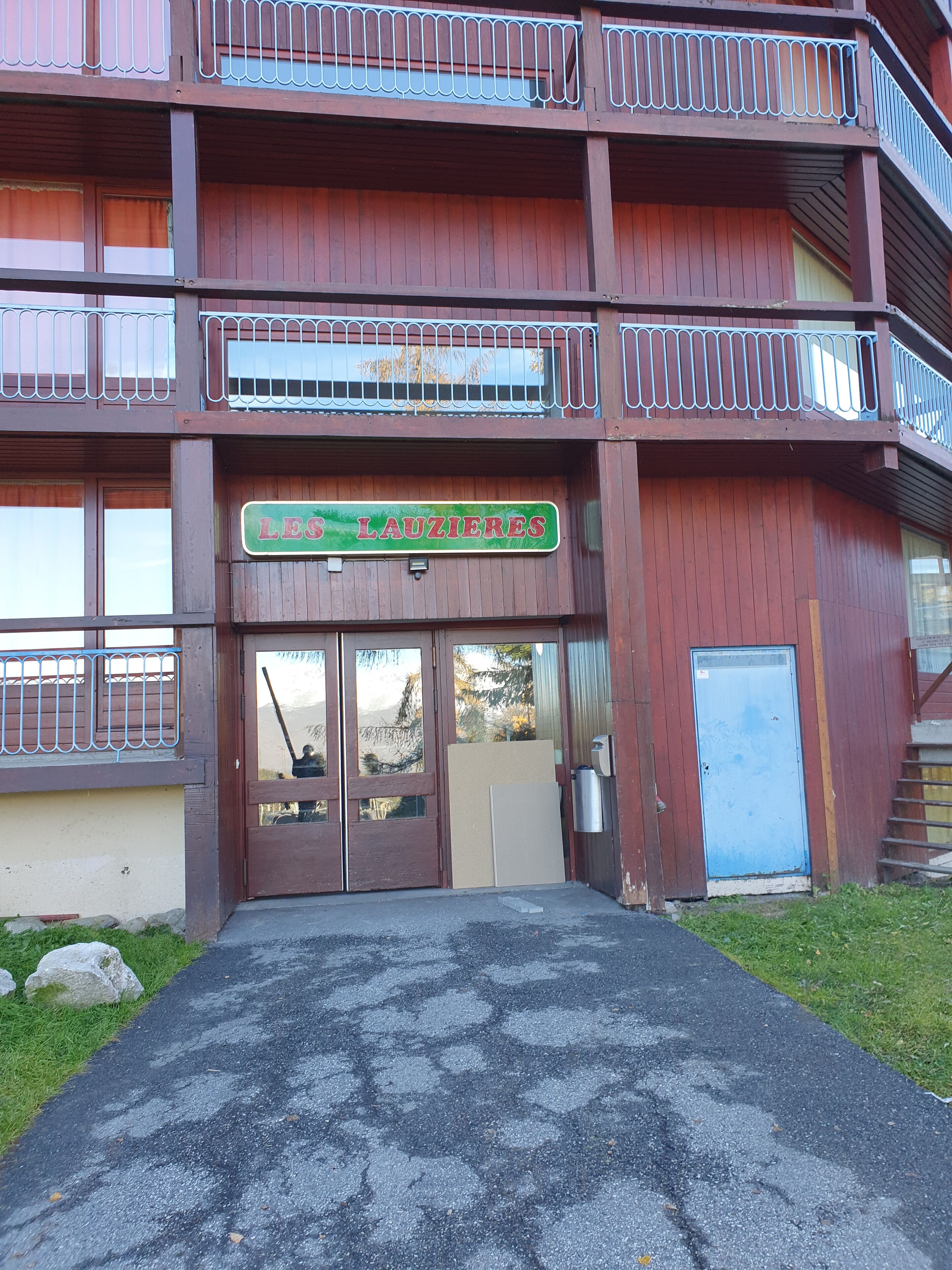 Un edificio in legno con un cartello che recita “LES LAUZIÈRES” e un cancello in metallo.
