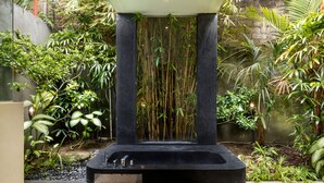 A modern bathroom with a black bathtub, a small sink, and a large window. - Villa Alice Dua by Villa Finder (Seminyak)