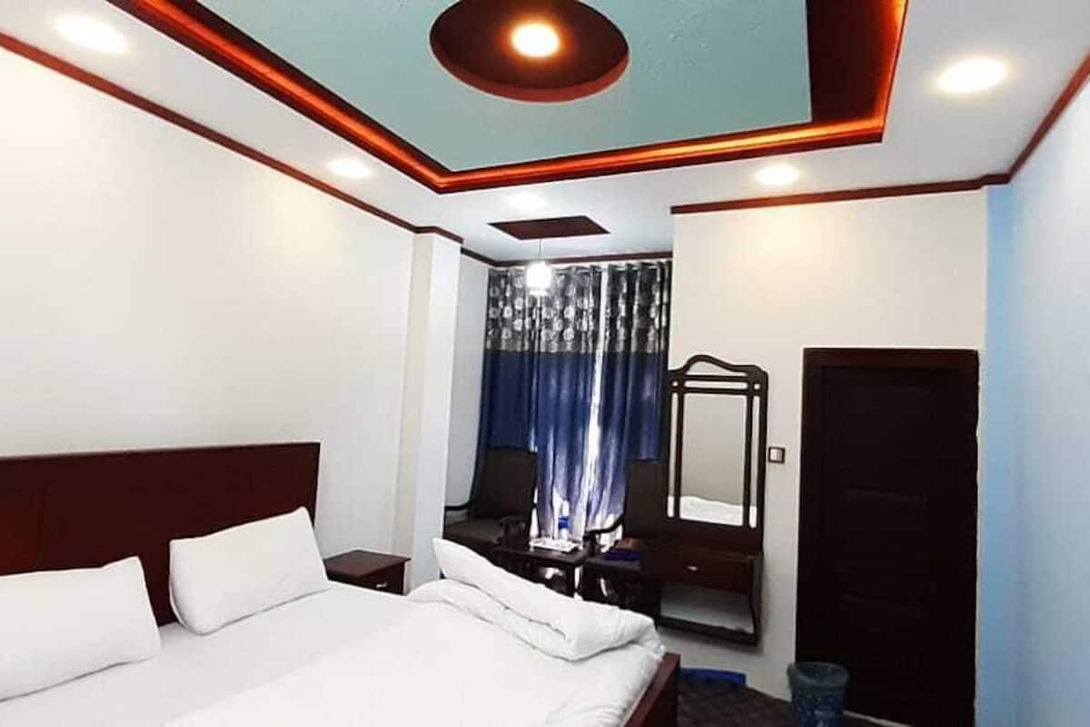 Ein Hotelzimmer mit einem großen Bett, einem Spiegel, einem Kleiderschrank und einem Fenster mit Vorhängen.
