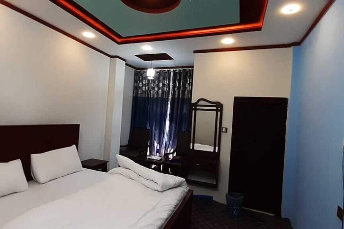 Ein Hotelzimmer mit einem großen Bett, einem Nachttisch, einem Spiegel und einer Tür.