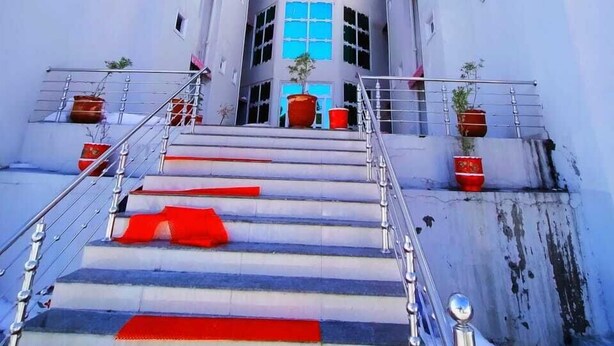 Una escalera conduce a un edificio de techo rojo y paredes blancas, con macetas de plantas en los peldaños.