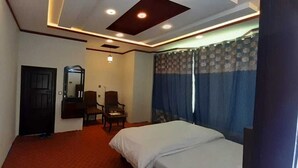 Una habitación de hotel con cama, escritorio, silla, espejo y puerta.