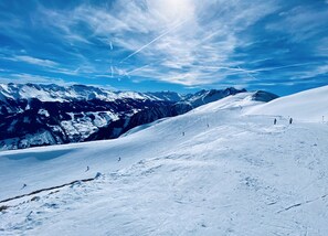 A snow-covered mountain slope with skiers and a clear sky.