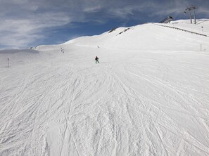 A snowy ski slope with a single skier descending.