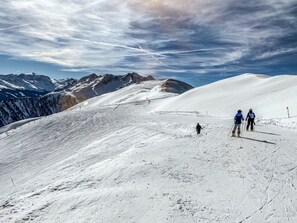 A snowy mountain slope with skiers and a clear sky.