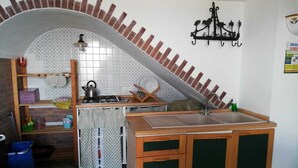 Una cocina compacta con salpicadero de azulejos, estufa a gas, lavamanos y armarios de madera.