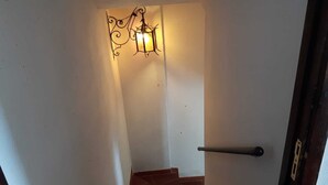 Una escalera con una lámpara en la pared y un picaporte.