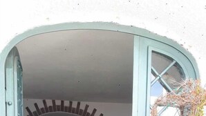 Un estrecho acceso que da a una cocina con salpicadero y suelo de azulejos, y una pequeña zona de estar.