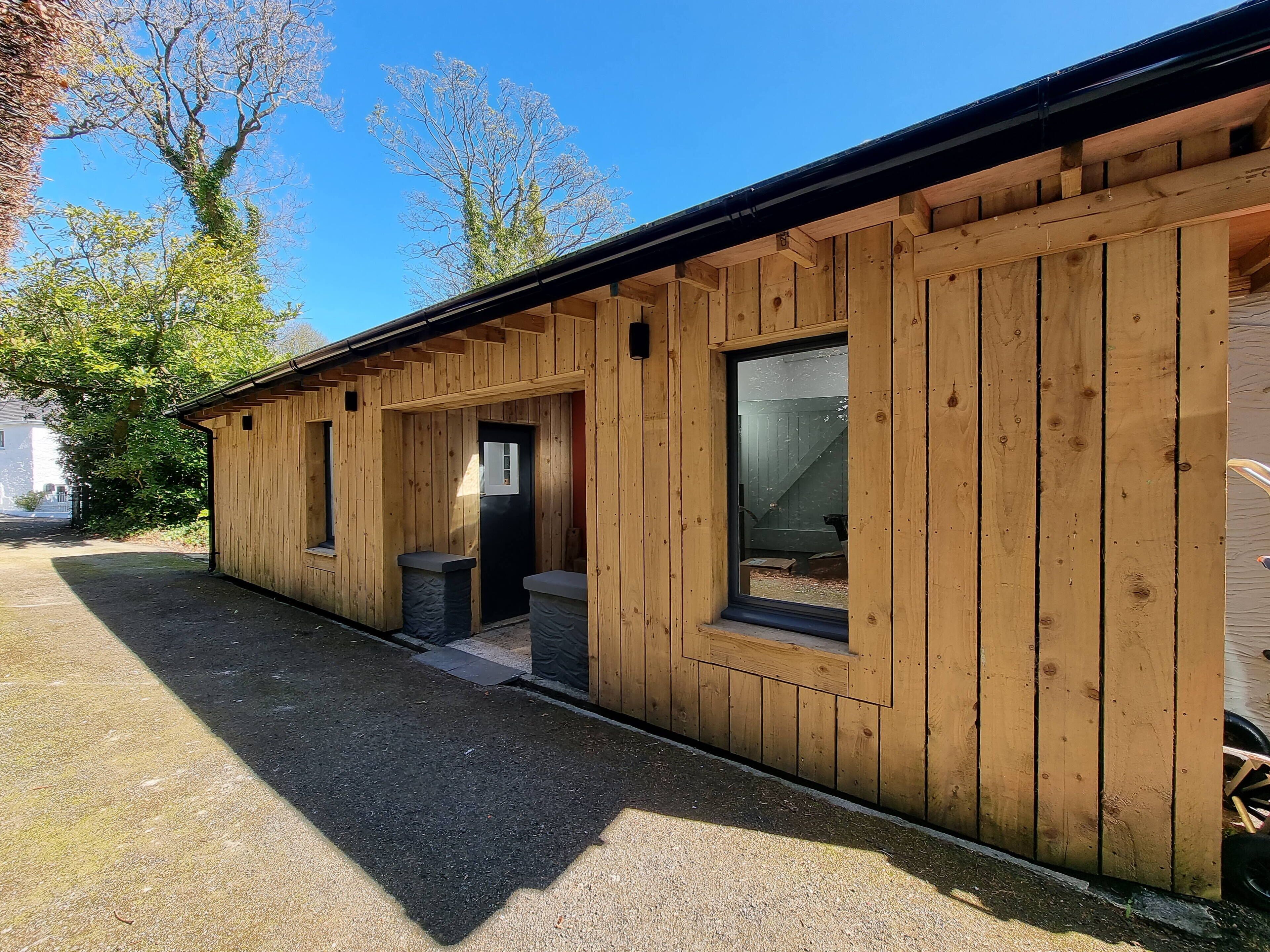 A wooden building with a covered porch, a door, and windows.