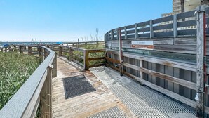 Terraza de madera con un letrero que indica ducharse y quitar la arena antes de entrar a la piscina.