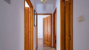 Un couloir avec des portes en bois et un sol carrelé.