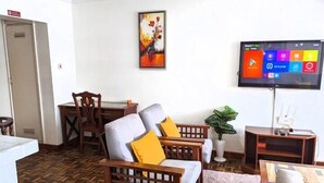 Ein Wohnzimmer mit Fernseher, Holzmöbeln und einem gemusterten Boden.