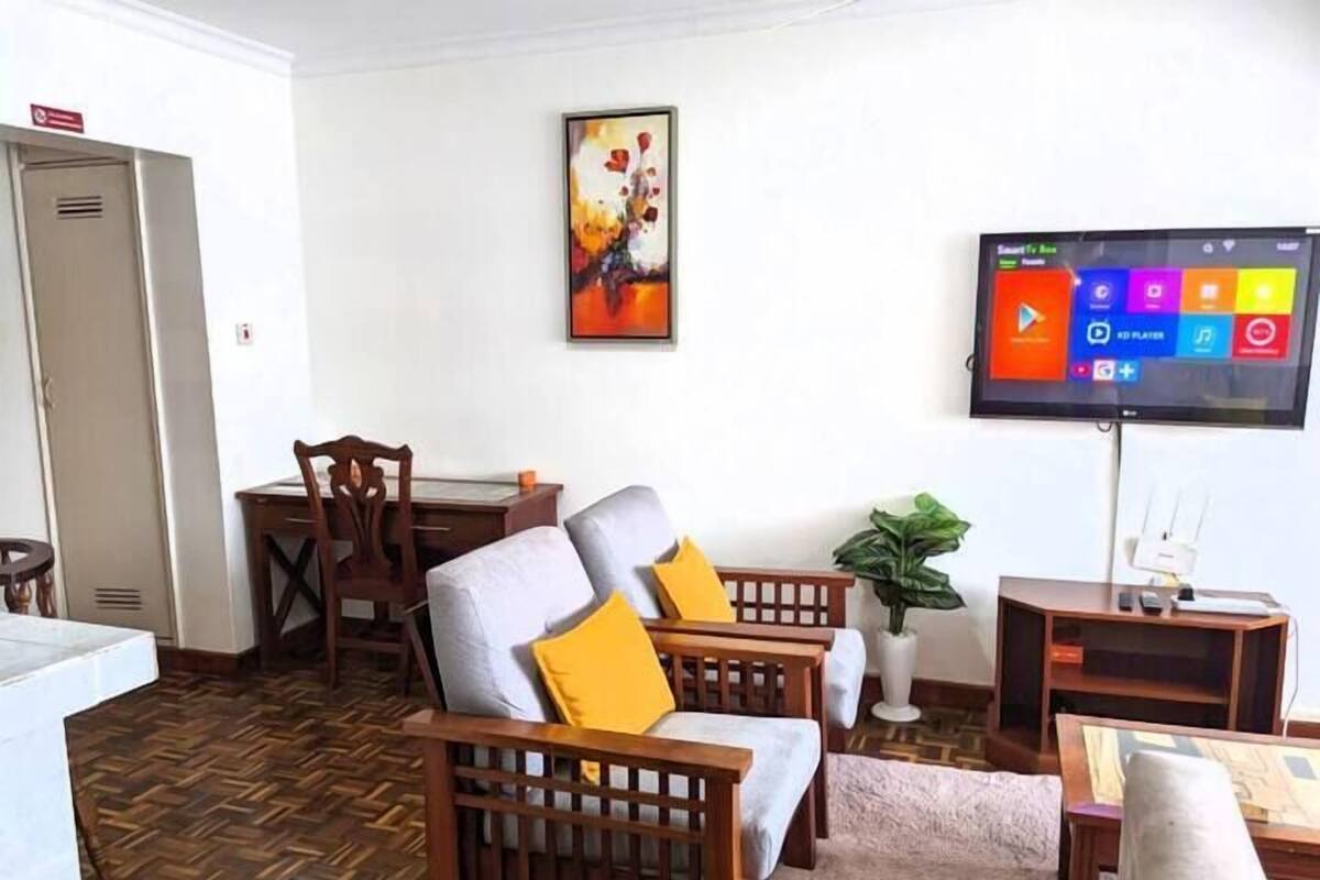 A living room with a television, wooden furniture, and a patterned floor.