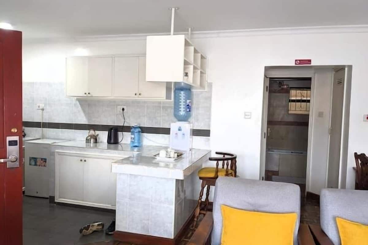 A compact living space with a kitchen area, a small dining table, and two sofas with yellow cushions.