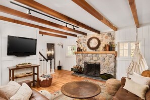 A living room with a stone fireplace, a television, and a hanging chair. - Cabin on Pikes Peak, Hot tub with Mountain Views (Cascade-Chipita Park)