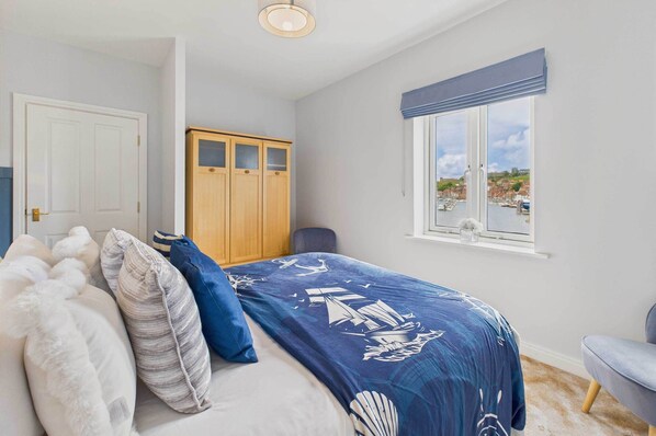 Quarto com cama, guarda-roupa, janela com vista para uma marina e uma cadeira.