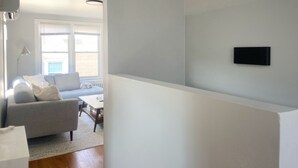 Una sala de estar moderna con un sofá gris, una mesa de centro y un televisor montado en la pared.