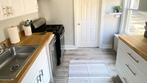 Una cocina con armarios blancos, una estufa, un fregadero y una alfombra estampada.