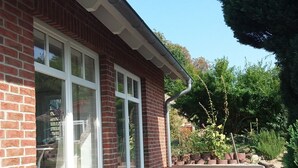 A brick building with large windows and a wooden deck. - Centrally located, quiet apartment with terrace and garden (Teschenhagen Sehlen)