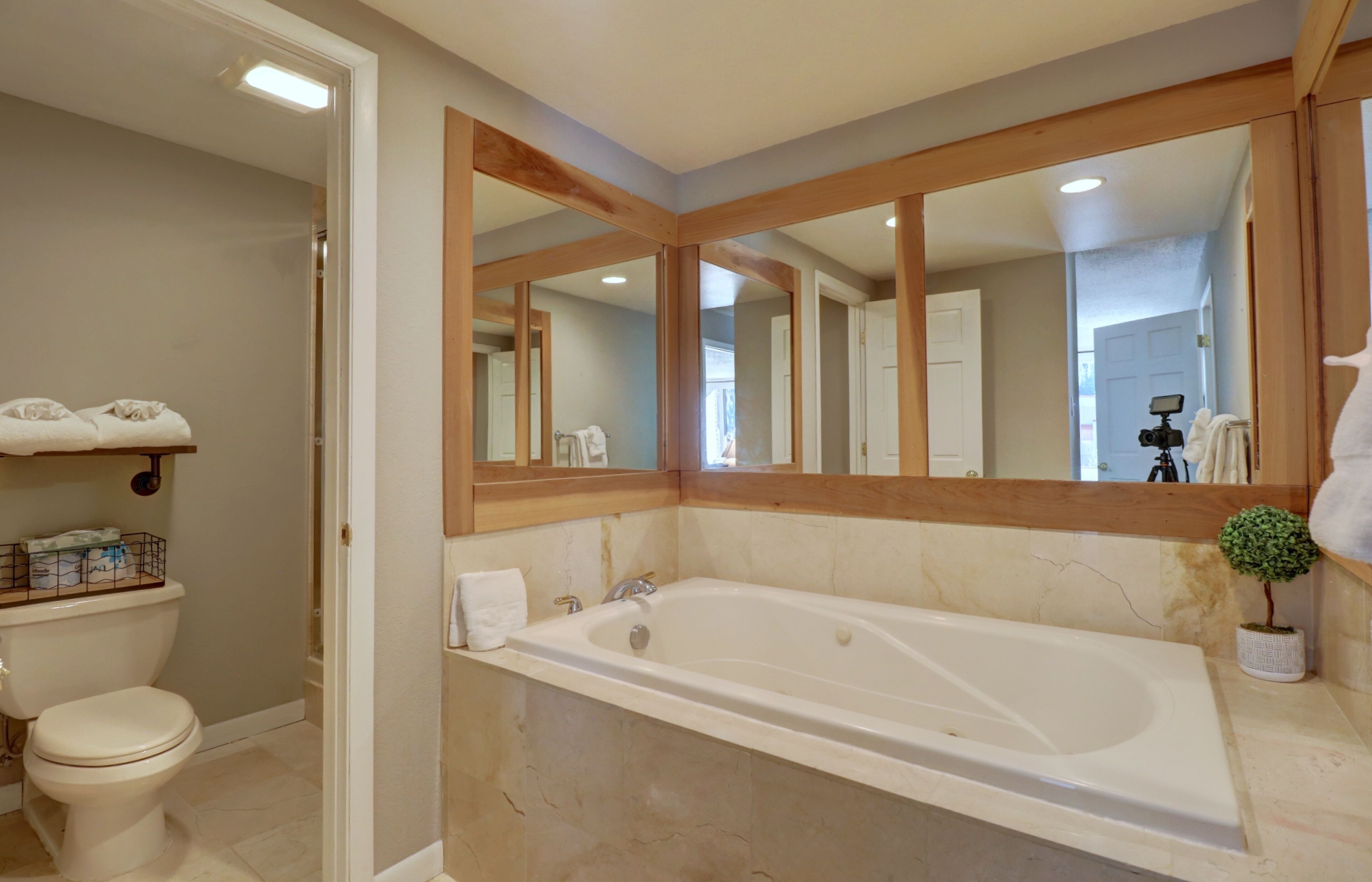 Ein Badezimmer mit einer großen Badewanne, einer Toilette, einem Waschbecken und einem Spiegel.