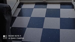 Parvekkeessa on ruutukuviollinen lattia, pöytä ja kaksi tuolia.