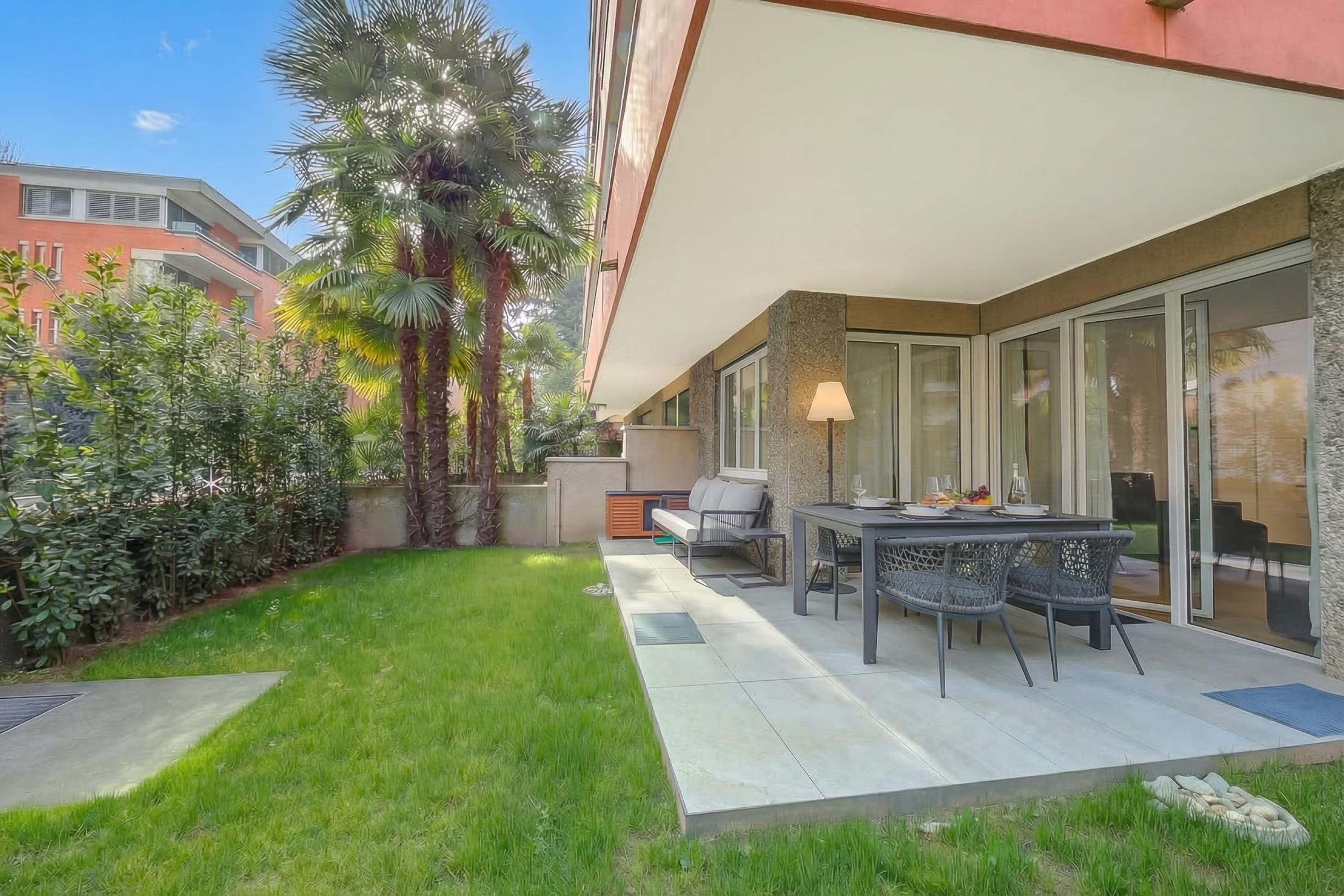 A patio with a table and chairs, a lamp, and a view of a building.