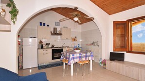 Un espacio habitable compacto con comedor, cocina y televisor sobre un mueble de madera.