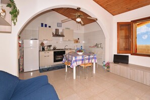 A compact living space with a dining area, kitchen, and a TV on a wooden cabinet. - Casa Apara (Scicli)