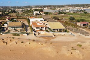 A residential area with houses, a sandy foreground, and a distant body of water. - Casa Apara (Scicli)