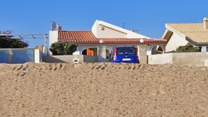 Una casa con techo de tejas rojas, una antena parabólica y un coche azul estacionado en la entrada.