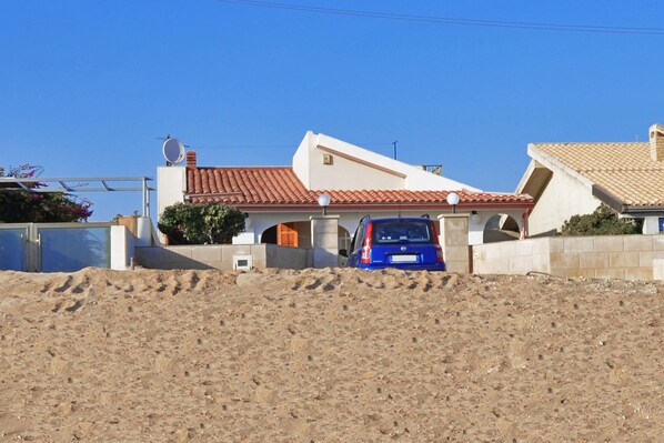 A house with a red-tiled roof, a satellite dish, and a blue car parked in the driveway. - Casa Apara (Scicli)