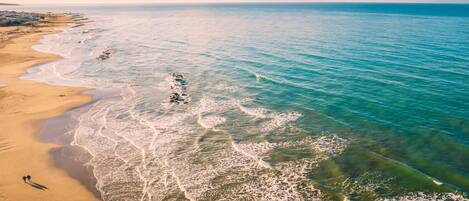 Vista aérea de una playa con aguas turquesas cristalinas y una costa arenosa.