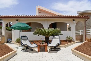 A patio area with two lounge chairs, a table, and a green umbrella. - Casa Apara (Scicli)