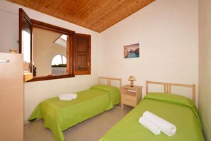 A room with two single beds, a wooden ceiling, a small bedside table with a lamp, and a mirror. - Casa Apara (Scicli)