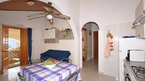 Una cocina con mesa, sillas, ventilador de techo y refrigerador.