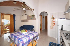 A kitchen with a table, chairs, a ceiling fan, and a refrigerator. - Casa Apara (Scicli)