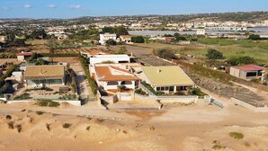 Zona residencial con casas, un primer plano arenoso y una masa de agua distante.