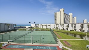 Un court de tennis avec une piscine attenante à un hôtel.